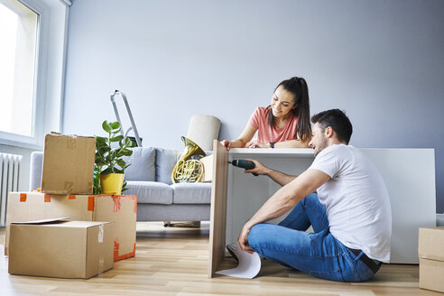 Ehepaar in neuer Wohnung beim Zusammenbau von Möbeln - BSZF00411