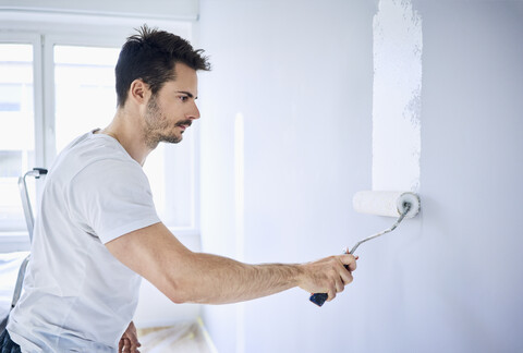 Man painting wall in apartment stock photo