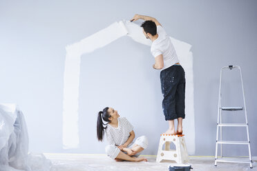 Couple painting house shape on wall in new apartment - BSZF00419