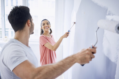 Glückliches Paar malt gemeinsam eine Wand in der Wohnung - BSZF00426