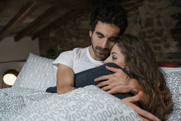 Romantic couple lying in bed hugging - CUF06826