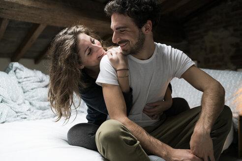 Romantisches Paar auf dem Bett sitzend und sich umarmend - CUF06827