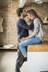 Young man kissing girlfriend on forehead at kitchen bench - CUF06831