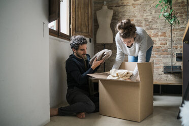 Young couple packing cardboard box on floor - CUF06833