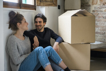 Young couple sitting on floor by cardboard boxes - CUF06845