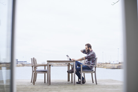 Young male designer using digital tablet on waterfront outside design studio stock photo