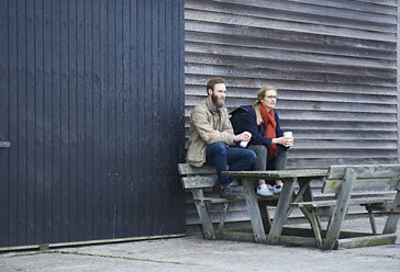 Männliche und weibliche Designer sitzen auf einer Bank außerhalb des Designstudios - CUF06872