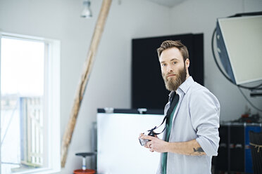 Portrait of male designer with digital camera in design studio - CUF06899