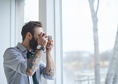 Männlicher Designer fotografiert durch das Fenster des Designstudios - CUF06901