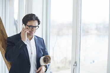 Männlicher Designer telefoniert mit seinem Smartphone im Fenster des Designstudios - CUF06909