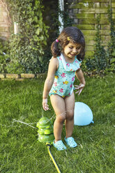 Junges Mädchen spielt im Garten, neben den Wassersprinklern - CUF06917