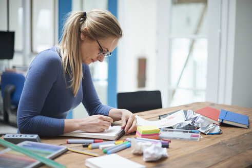 Eine Designerin macht sich Notizen am Schreibtisch eines Designstudios - CUF06926