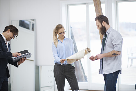 Innenarchitektenteam betrachtet eine Tapetenrolle im Designstudio, lizenzfreies Stockfoto