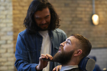 Friseurin im Friseursalon trimmt den Bart eines Kunden - CUF06982