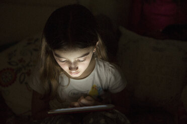 Mädchen in der Dunkelheit, beleuchtet vom Licht eines digitalen Tablets - CUF07042