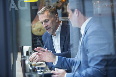 Zwei Geschäftsleute diskutieren auf einem Fensterplatz im Restaurant - CUF07045