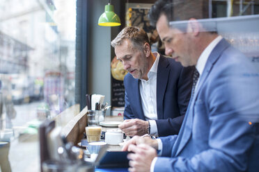 Two businessmen having working lunch in restaurant - CUF07047