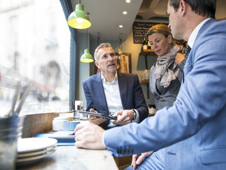 Businessmen and woman having discussion in restaurant window seat - CUF07050