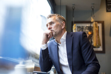 Älterer Geschäftsmann schaut aus dem Fenster eines Restaurants - CUF07053