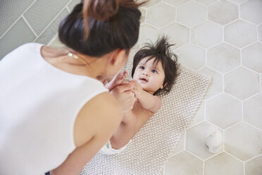 Over shoulder view of woman playing with baby daughter's feet on bathroom floor - CUF07104