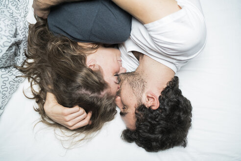 Draufsicht auf ein junges Paar, das im Bett liegt und sich umarmt - CUF07135