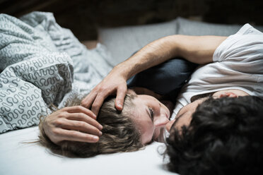 Young couple lying in bed embracing face to face - CUF07136