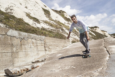 Junger männlicher Skateboarder fährt mit dem Skateboard die Klippe hinunter - CUF07157