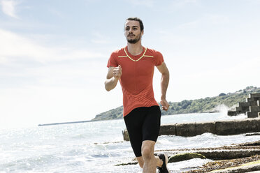 Young male runner running along beach - CUF07160