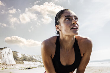 Exhausted young female runner taking a break on beach - CUF07178