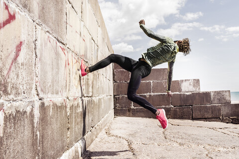 Young man, free running, outdoors, running up side of wall stock photo