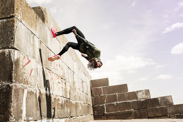 Young man, free running, outdoors, somersaulting from side of wall - CUF07186