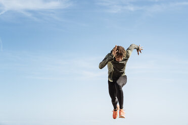 Young man running outdoors, mid air - CUF07193