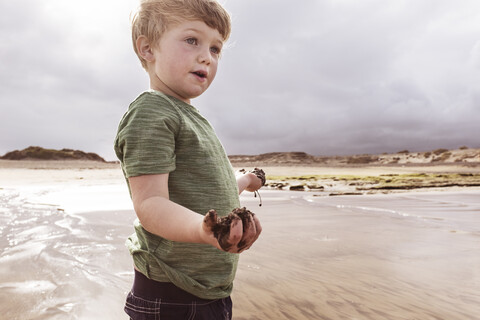 Young boy on beach, holding wet sand, Santa Cruz de Tenerife, Canary Islands, Spain, Europe stock photo