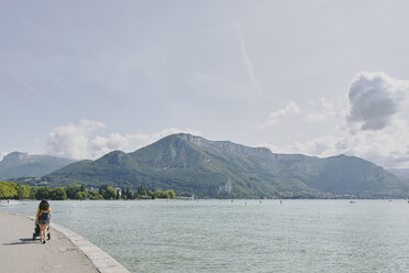 Rückansicht einer Spaziergängerin mit Kinderwagen am Ufer des Annecy-Sees, Annecy, Auvergne-Rhone-Alpes, Frankreich - CUF07279