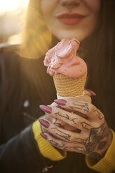 Junge Frau mit Eiscreme in der Hand, Tätowierungen auf der Hand, Mittelteil, Nahaufnahme - CUF07294