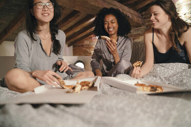 Mädchen sitzen auf dem Bett und essen Pizza - CUF07436