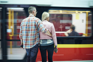 Rückansicht eines jungen Paares, das an der Straßenbahnhaltestelle der Stadt wartet - CUF07489