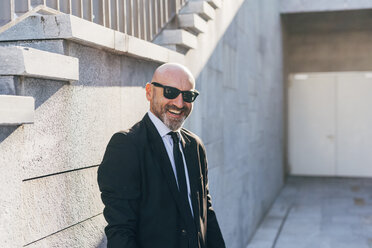 Porträt eines reifen Geschäftsmannes im Freien, neben Stufen stehend, lächelnd - CUF07499