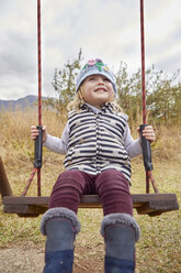 Girl sitting on swing in rural setting - CUF07516