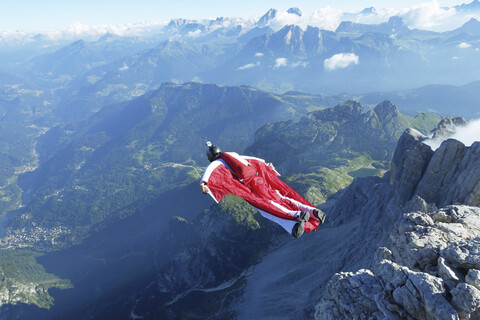 Männlicher Wingsuit-BASE-Springer beim Absprung vom Klippenrand, lizenzfreies Stockfoto