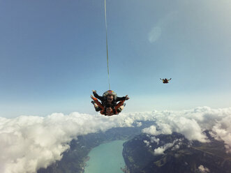 Portrait of tandem skydivers above clouds and landscape - CUF07530