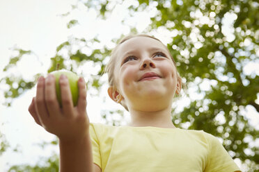 Junges Mädchen, im Freien, mit Apfel in der Hand, flacher Blickwinkel - CUF07534