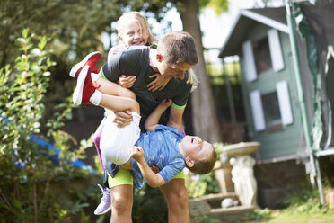 Family playfighting in garden - CUF07678