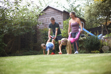 Family in garden, having wheelbarrow race - CUF07691