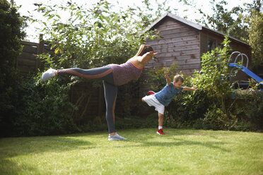 Mutter und Sohn üben im Garten, stehend in Yoga-Position - CUF07696