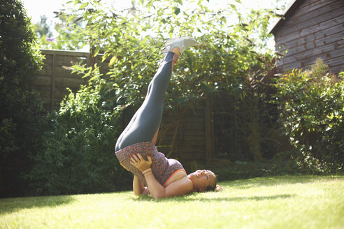 Mature woman exercising in garden, doing shoulder stand - CUF07697