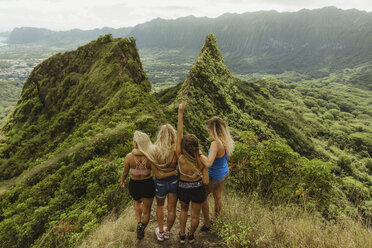 Rear view of friends on grass covered mountain, Oahu, Hawaii, USA - ISF01456