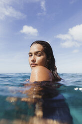 Frau im Meer schaut über die Schulter in die Kamera, Oahu, Hawaii, USA - ISF01461