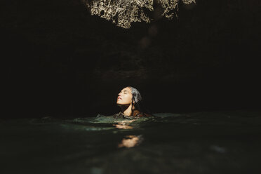 Frau in wassergefüllter Höhle, Augen geschlossen, wegschauend, Oahu, Hawaii, USA - ISF01462
