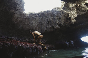 Junge Frau klettert auf Felsen, Mermaid Caves, Oahu, Hawaii, USA - ISF01469